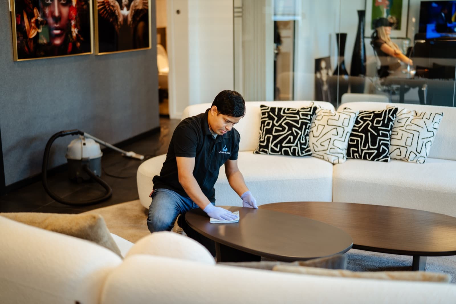 Living Clean renholder tørker av sofabord i moderne kontorlounge